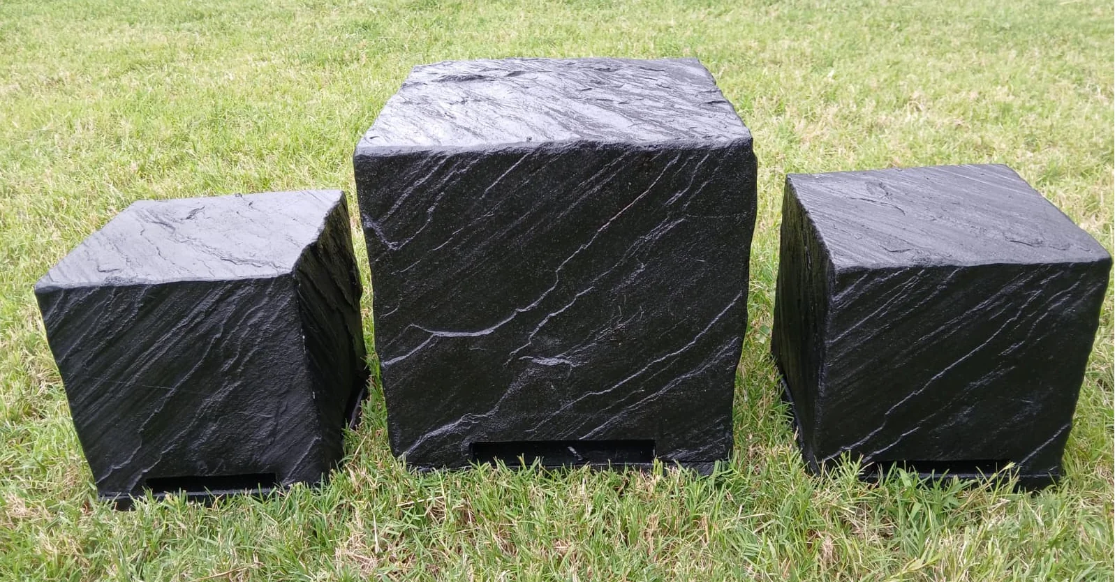 Three AudioSTONE Qb-Series speakers in black on grass